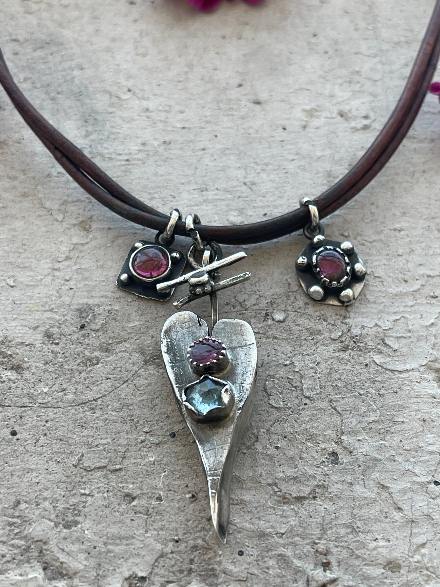 NECKLACE 35: STERLING SILVER HALLOW FORM HEART WITH PINK AND BLUE GEMS. 2 MORE PINK GEMS ON LEATHER